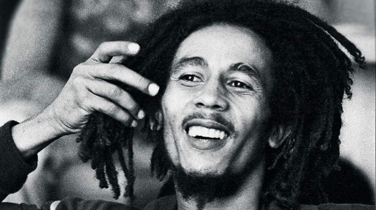 Portrait en noir et blanc de Bob Marley souriant, la main près de ses dreadlocks Image