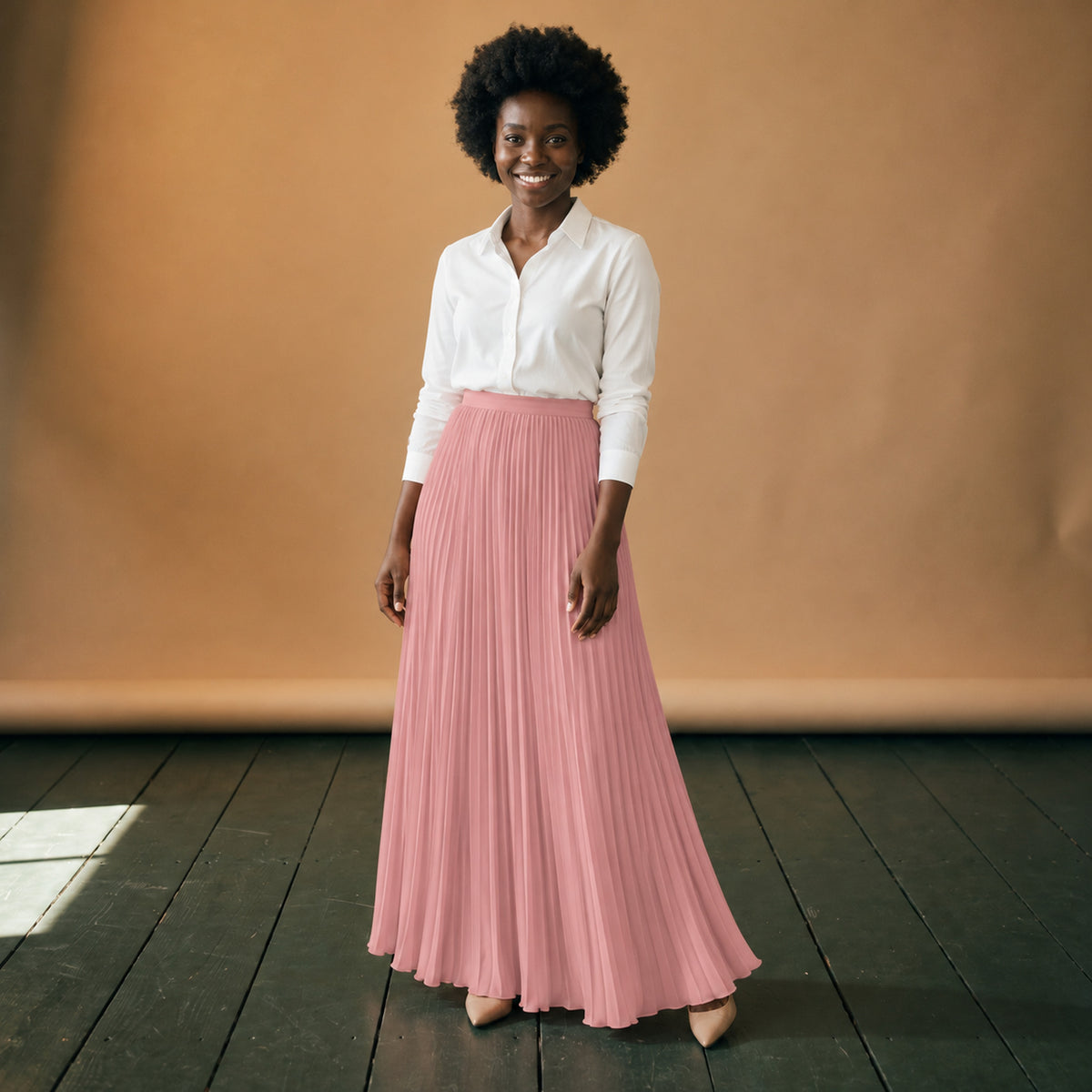 Jupe longue années 80 plissée rose taille haute portée en studio avec un chemisier blanc, vue de face Image
