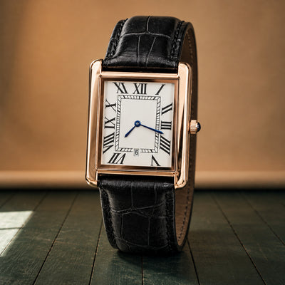 Gros plan sur le cadran blanc à chiffres romains et le bracelet noir texturé de la montre rectangulaire homme