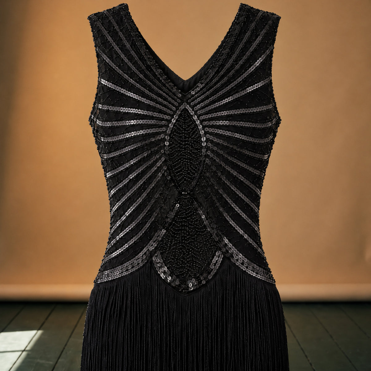 Gros plan sur les paillettes géométriques du col et les franges de la robe charleston noire Image