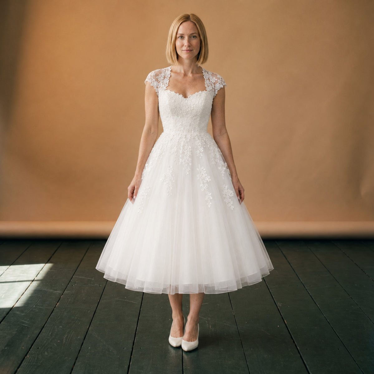 Robe de mariée courte en dentelle et tulle portée en studio, vue en pied de face Image